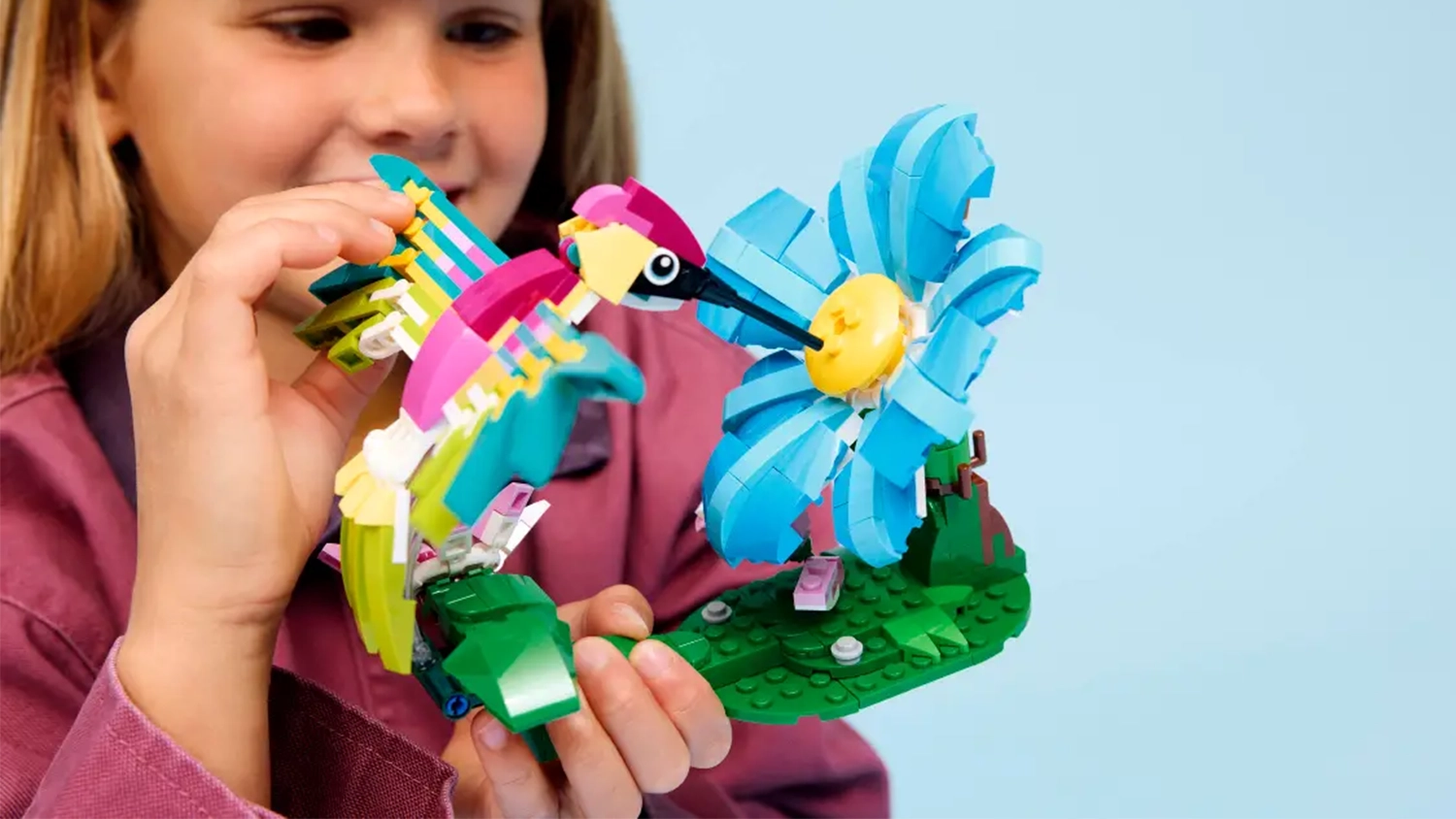 D&iacute;vka drž&iacute; v ruce model ze stavebnice LEGO&reg; Creator 3 v 1 31384 Divok&aacute; zv&iacute;řata: Barevn&yacute; kolibř&iacute;k