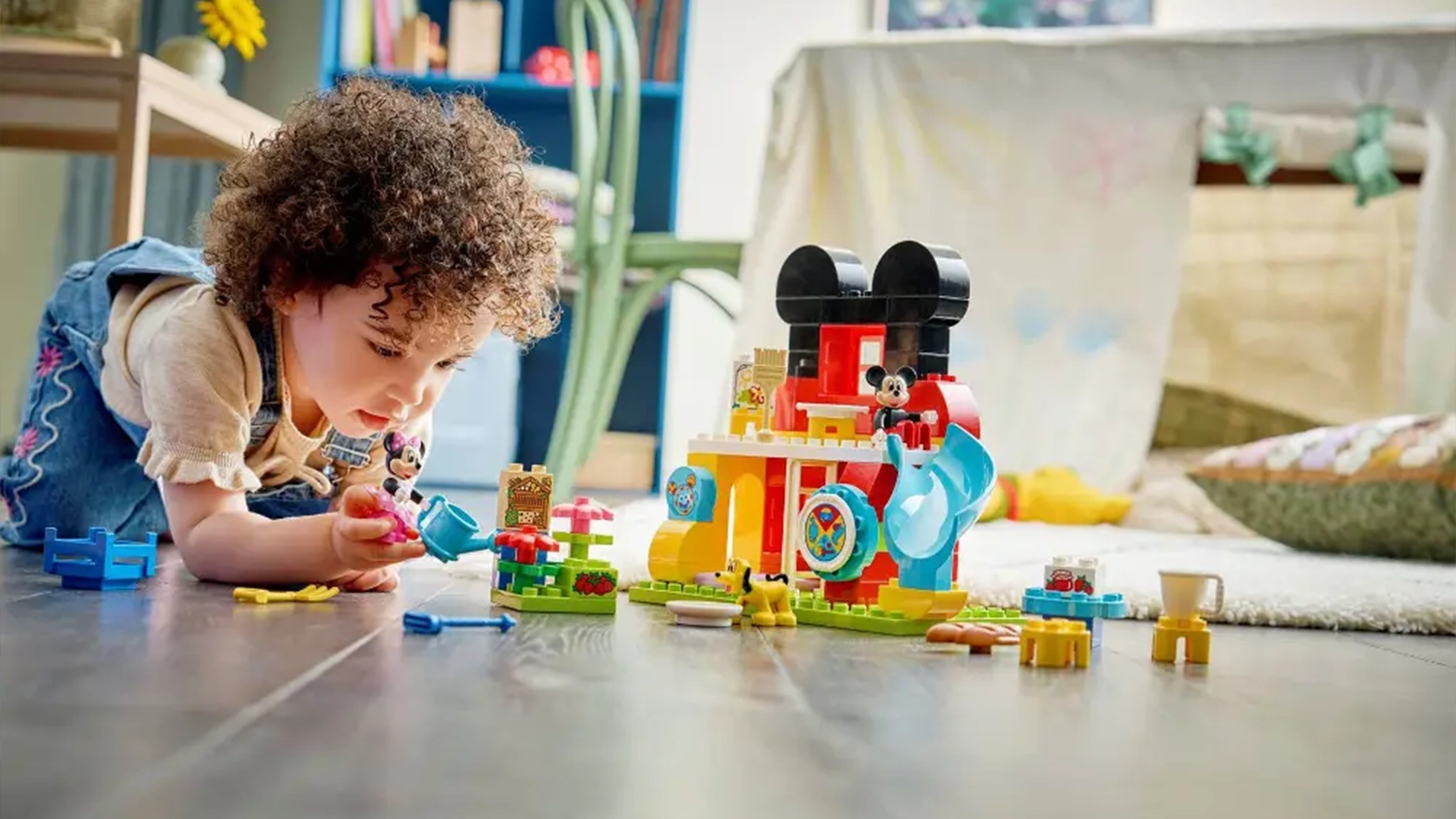 Holčička si hraje se stavebnic&iacute; LEGO&reg; DUPLO&reg; | Disney (10465) a s figurkou Minnie Mouse zal&eacute;v&aacute; zahr&aacute;dku.