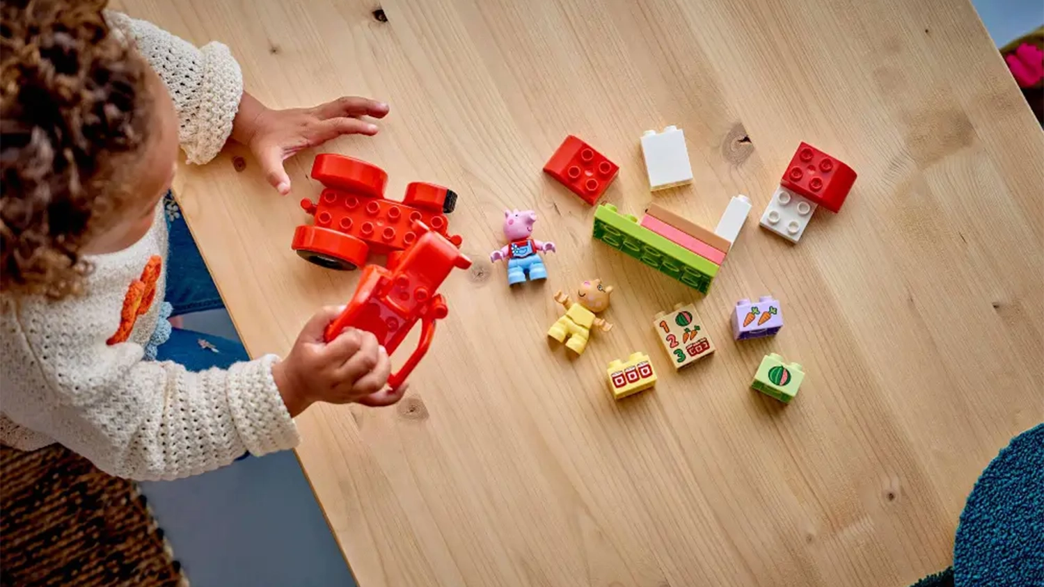 Holčička sestavuje stavebnici LEGO® DUPLO® Prasátko Peppa 10468 Traktor a tržnice