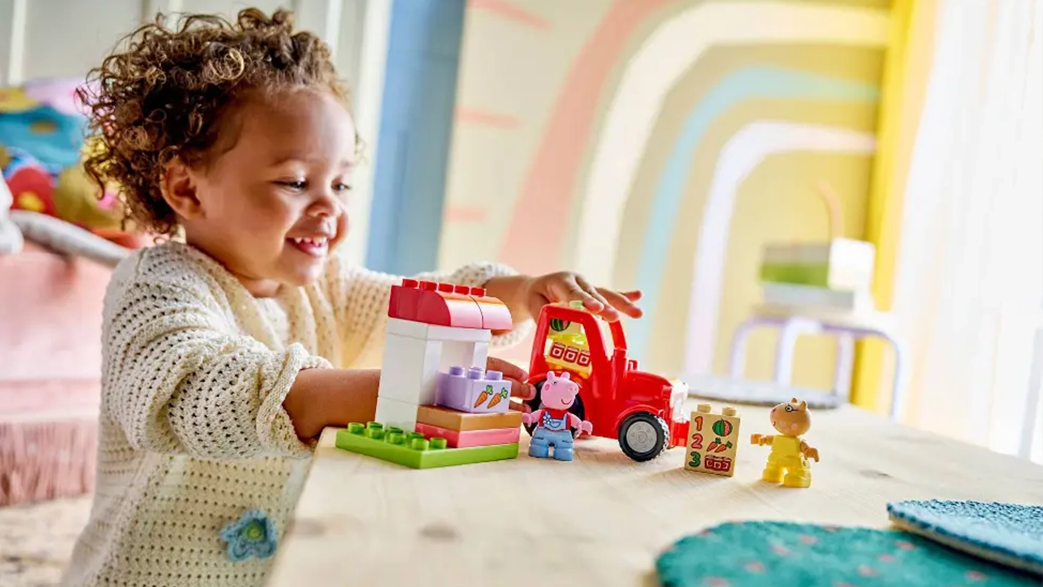 Smějící se holčička si hraje se stavebnicí LEGO® DUPLO® Prasátko Peppa 10468 Traktor a tržnice.