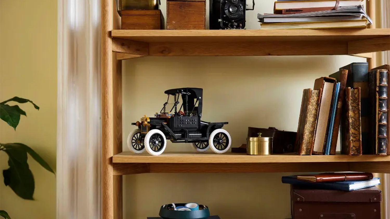 Replika vozu ze stavebnice LEGO® Icons 11376 Ford Model T vystavená na polici vedle knih