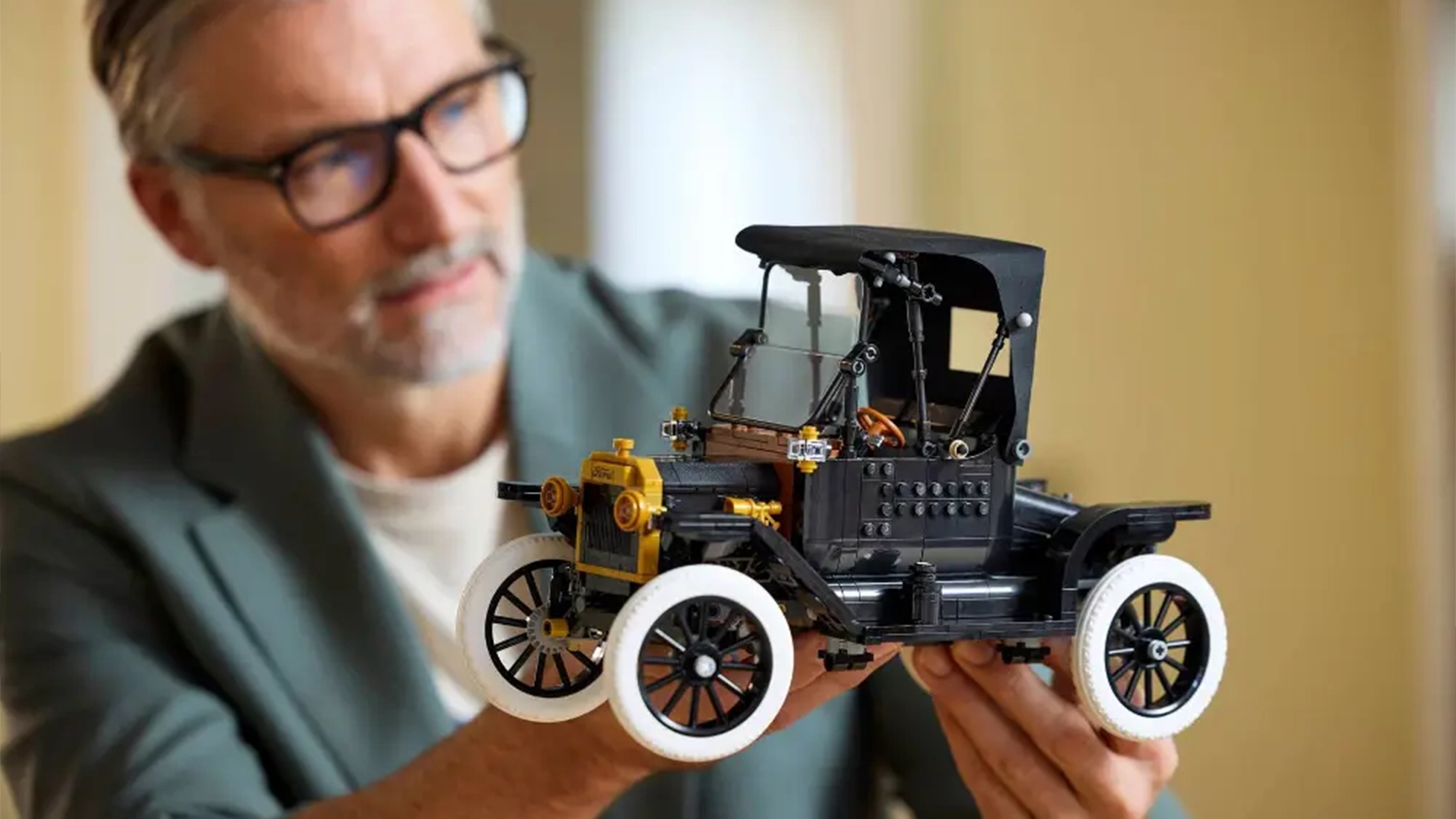 Muž obdivuje repliku vozu ze stavebnice LEGO® Icons 11376 Ford Model T, kterou drží v rukou.