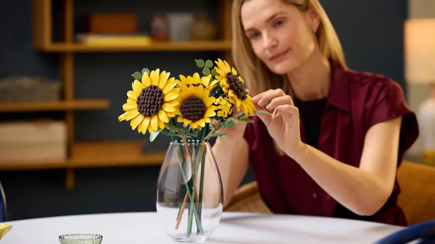 Žena aranžuje kytici slunečnic ze LEGO&reg; Botanicals (11502), kterou m&aacute; ve v&aacute;ze.