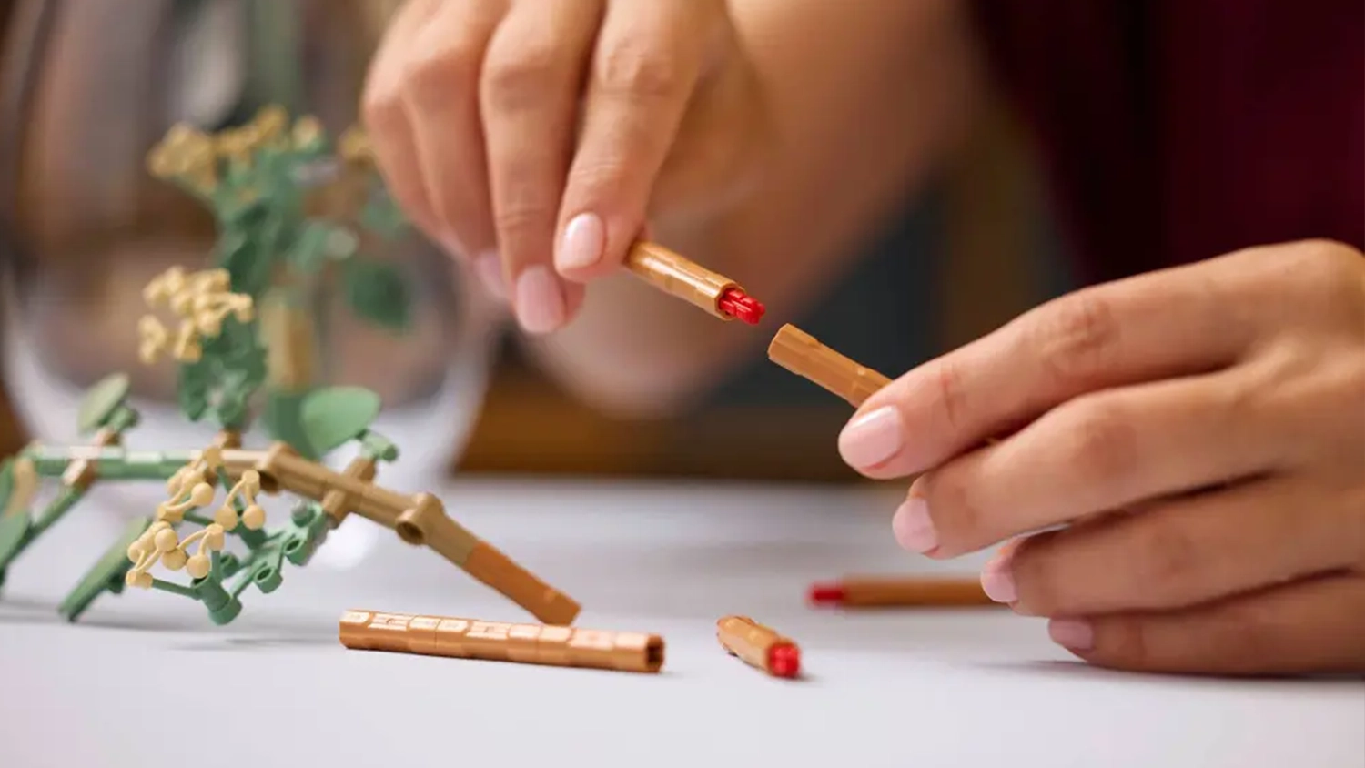Žensk&eacute; ruce spojuj&iacute;c&iacute; stonky eukalyptu ze stavebnice LEGO&reg; Botanicals 11502 Kytice slunečnic