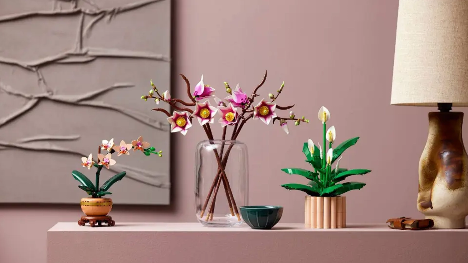 Vetvičky magnólie zo stavebnice LEGO® Botanicals (11510) vo váze vedľa ďalších rastlín z kolekcie LEGO® Botanicals v kvetináčoch.