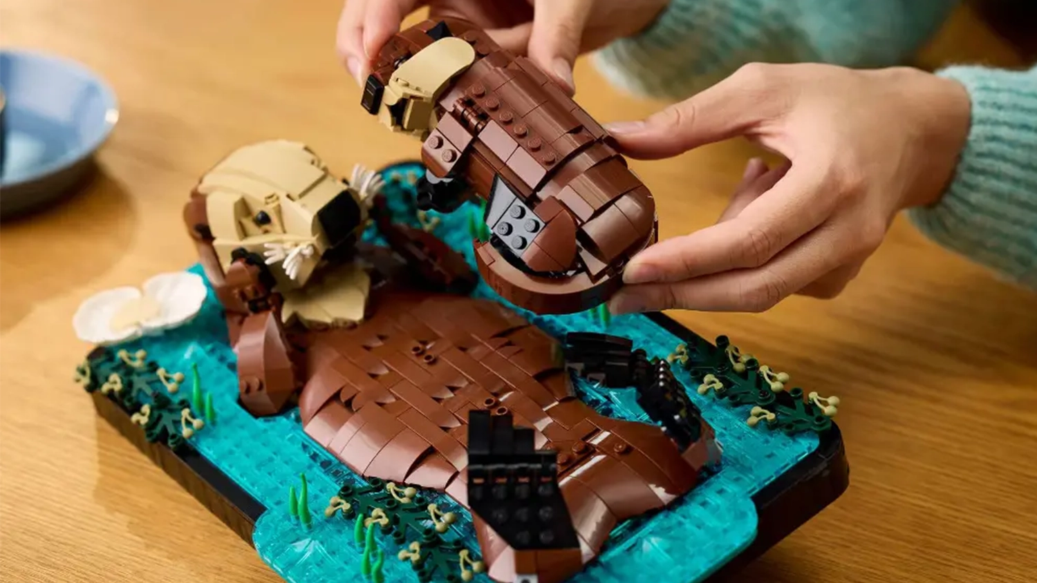 Žena přikl&aacute;d&aacute; ml&aacute;dě na břicho vydř&iacute; matce ze stavebnice LEGO&reg; Ideas 21366 Plavaj&iacute;c&iacute; mořsk&eacute; vydry.