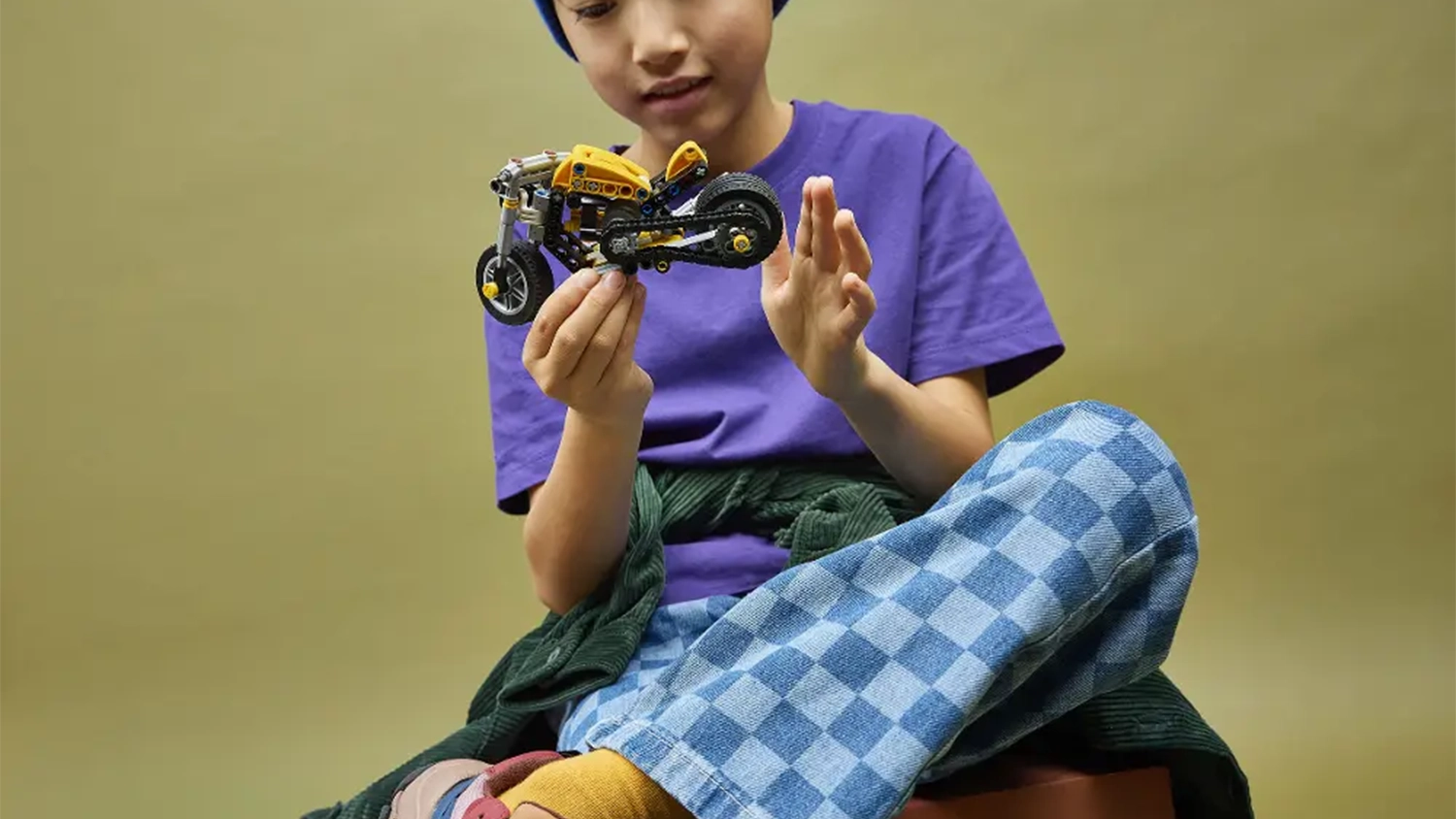 Chlapec si prohlíží žlutou motorku ze stavebnice LEGO® Technic (42225), kterou drží v ruce