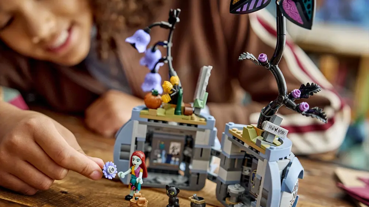 Usmievajúce sa dievča sa hrá so stavebnicou LEGO® | Disney 43288 Sallyin kvetináč a má odhalený vnútorný priestor s doplnkami.