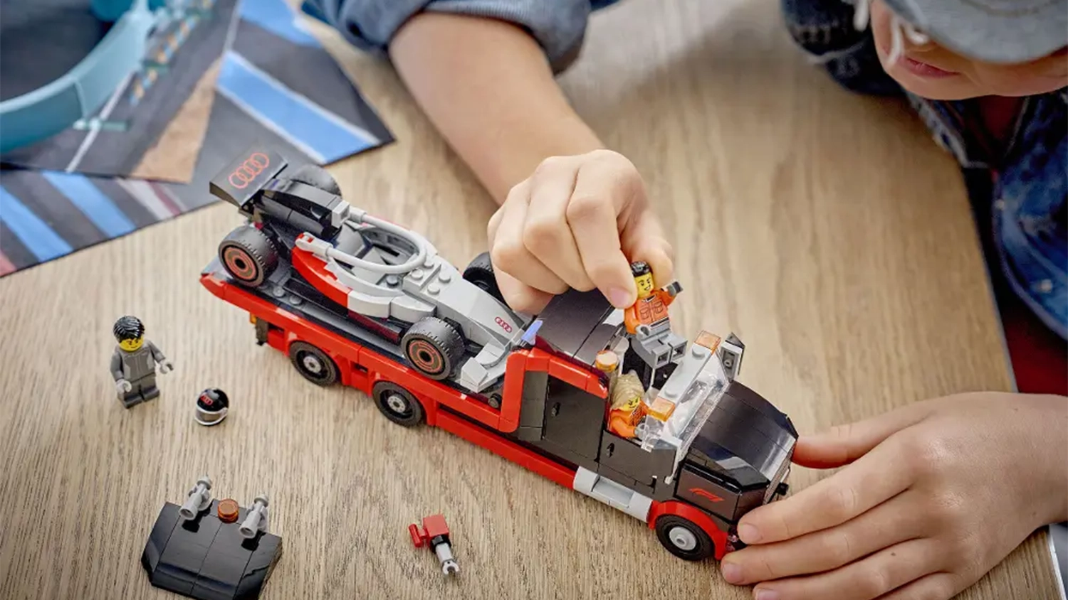 Chlapec si hraje se stavebnicí LEGO® City 60493 Výstavní náklaďák F1® se závodním autem Audi F1®.