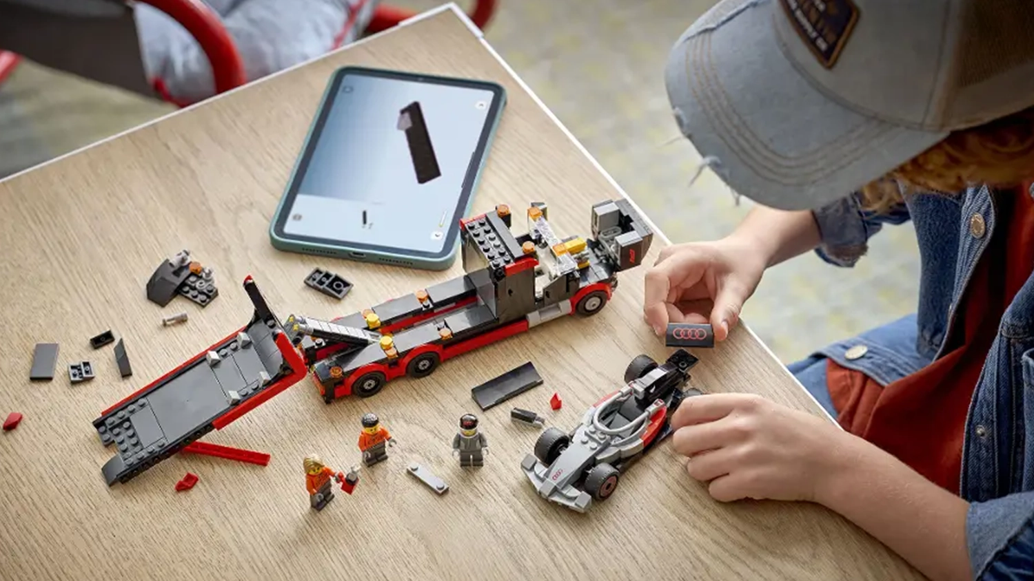Chlapec sestavuje stavebnici LEGO® City 60493 Výstavní náklaďák F1® se závodním autem Audi F1® s pomocí návodu v aplikaci LEGO® Builder na tabletu.
