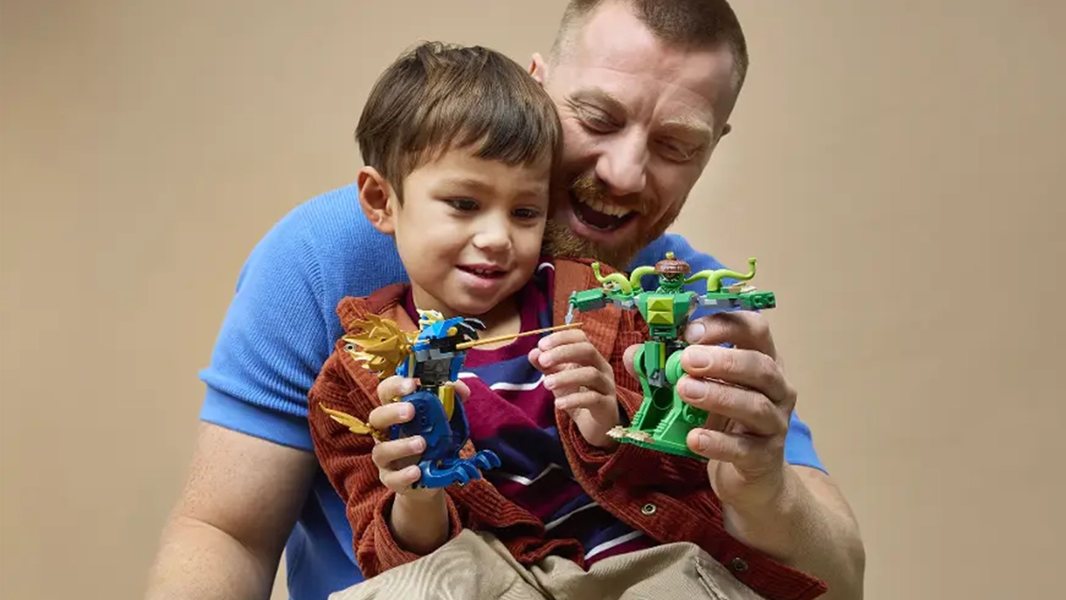Otec se synem sehr&aacute;vaj&iacute; bitvu mezi 2 figurkami v robotick&yacute;ch oblec&iacute;ch ze stavebnice LEGO&reg; NINJAGO&reg; (71853).