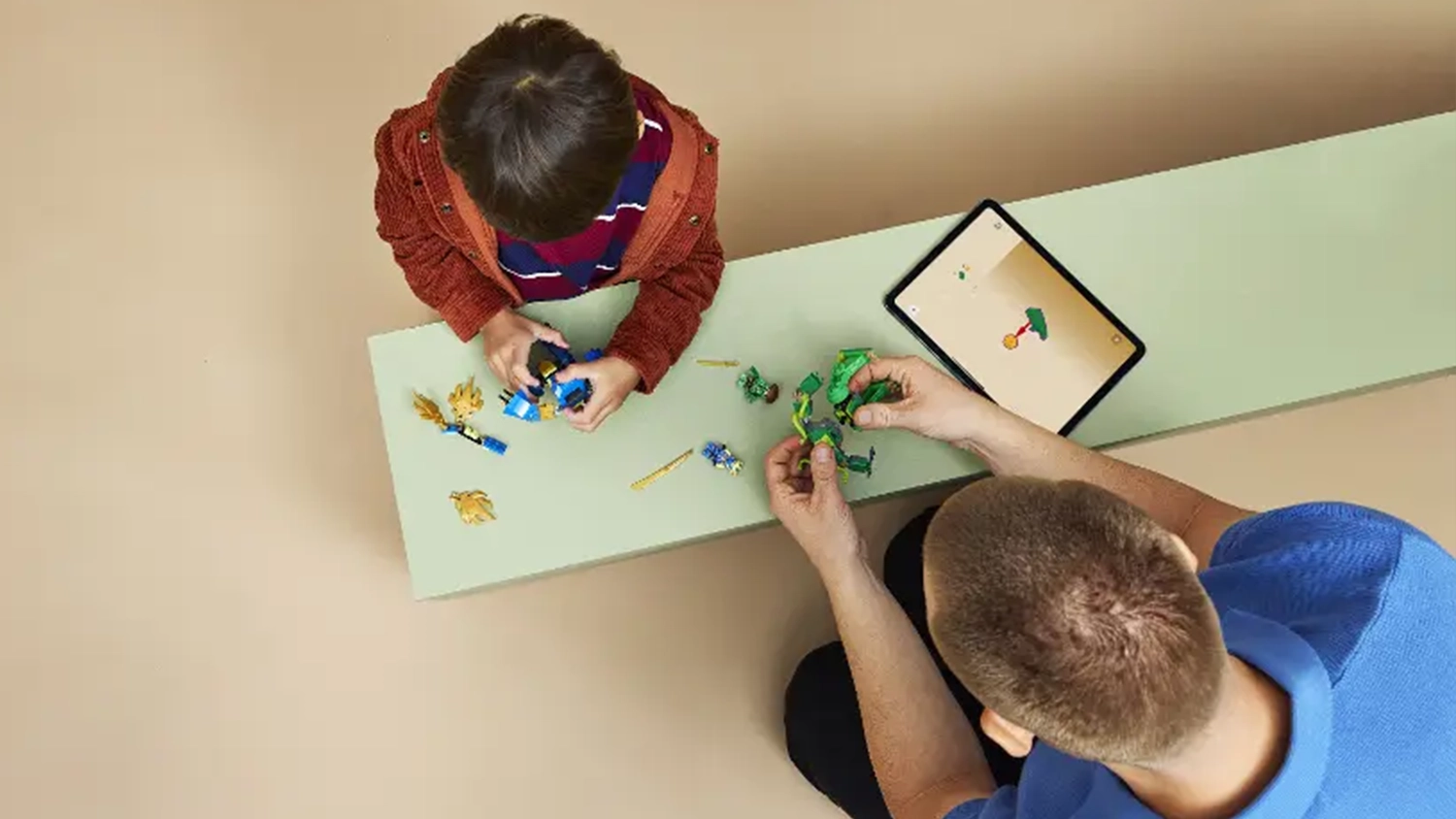 Otec pom&aacute;h&aacute; synovi sestavit stavebnici LEGO&reg; NINJAGO&reg; 71853 Jay a boj v drač&iacute;m robotick&eacute;m obleku s pomoc&iacute; n&aacute;vodu v aplikaci LEGO&reg; Builder na tabletu.