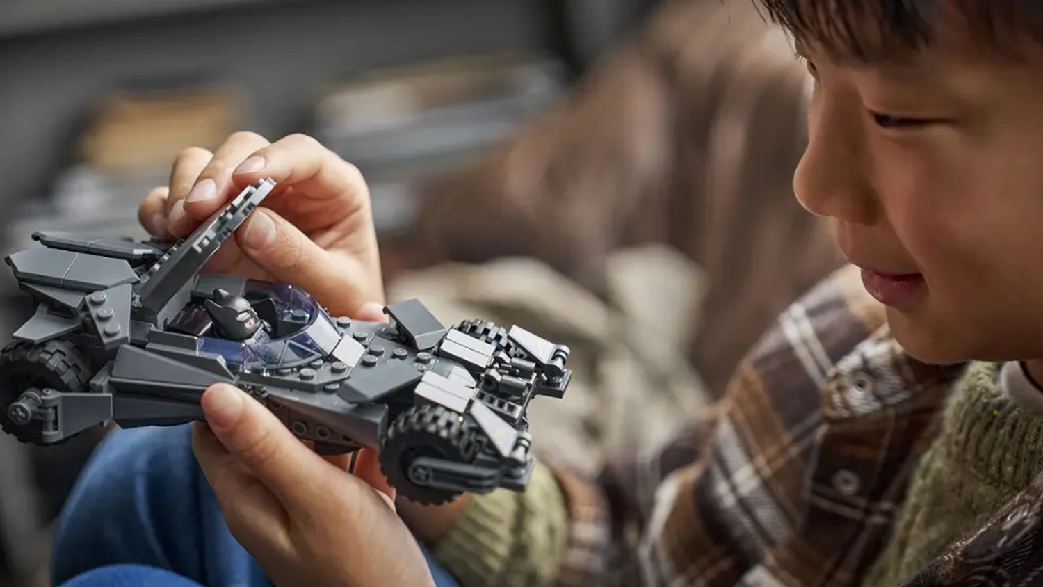 Usm&iacute;vaj&iacute;c&iacute; se chlapec drž&iacute; v ruce model Batmobilu ze stavebnice LEGO&reg; DC Batman&trade; (76331) s otevřen&yacute;m kokpitem a minifigurkou uvnitř.