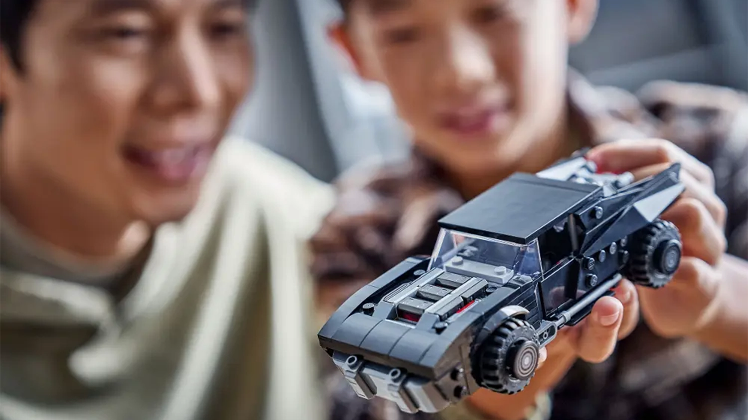 Dva usm&iacute;vaj&iacute;c&iacute; se chlapci obdivuj&iacute; model Batmobilu ze stavebnice LEGO&reg; DC Batman&trade; (76332).