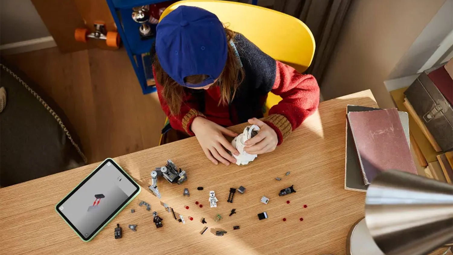 Dieťa skladá stavebnicu LEGO® Star Wars™ 75444 Útok AT-RT™ s pomocou návodu v aplikácii LEGO® Builder na tablete.