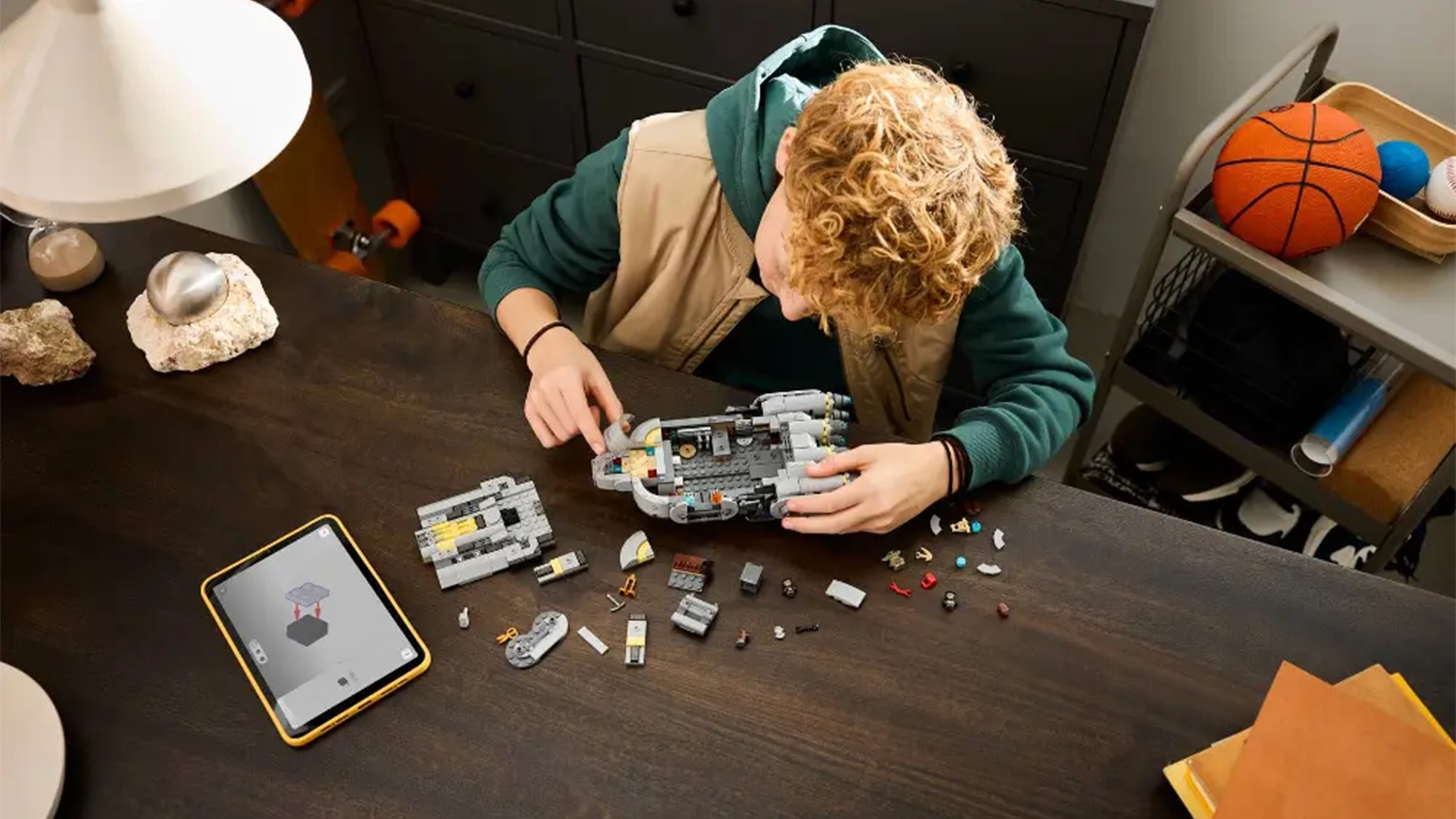 Chlapec sed&iacute;c&iacute; u stolu sestavuje stavebnici LEGO&reg; Star Wars&trade; 75445 Anzellansk&aacute; vesm&iacute;rn&aacute; loď.
