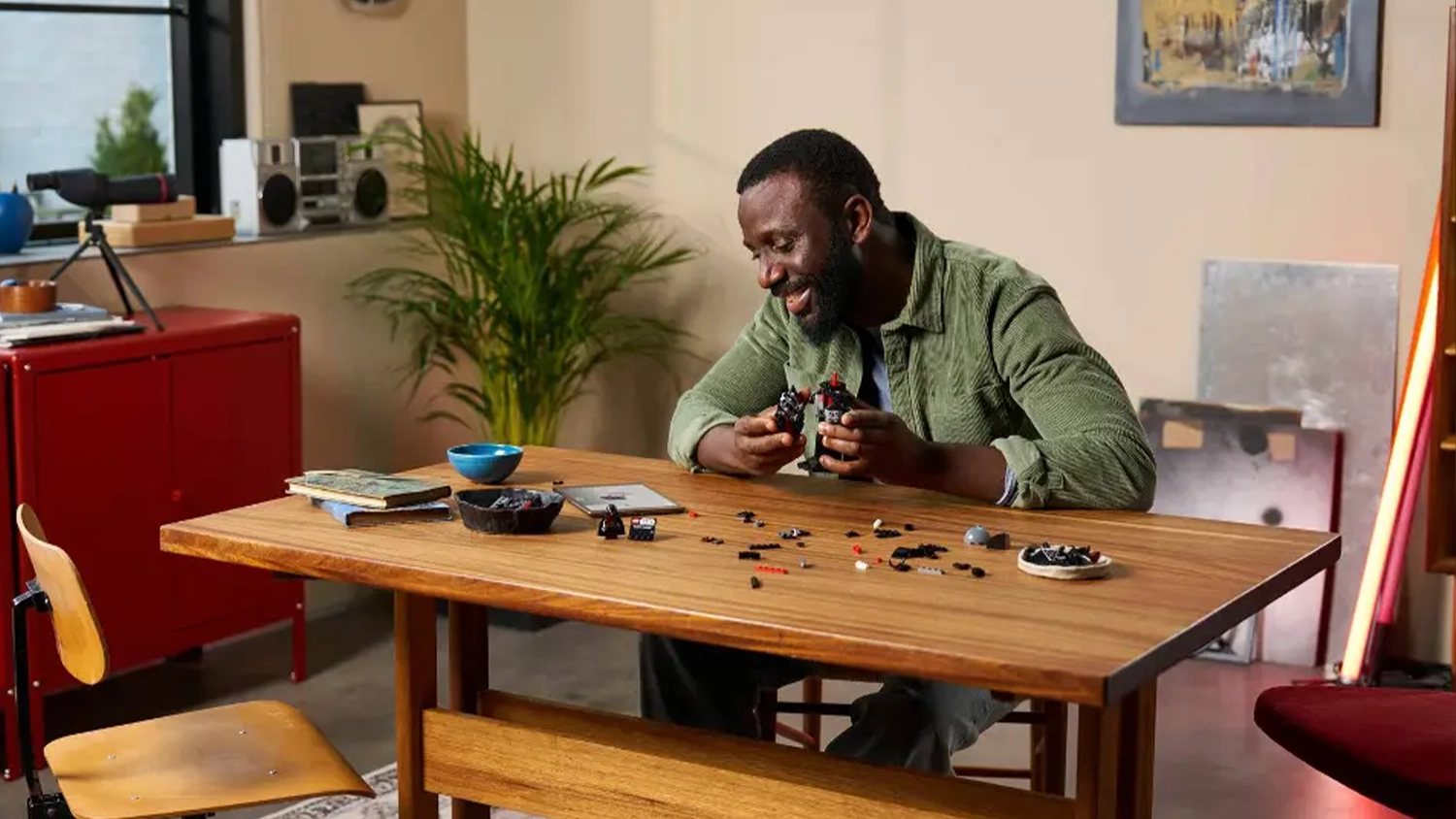 Muž sedící u stolu sestavuje stavebnici LEGO® Star Wars™ 75439 Busta Darth Vadera s pomocí návodu v aplikaci LEGO® Builder.