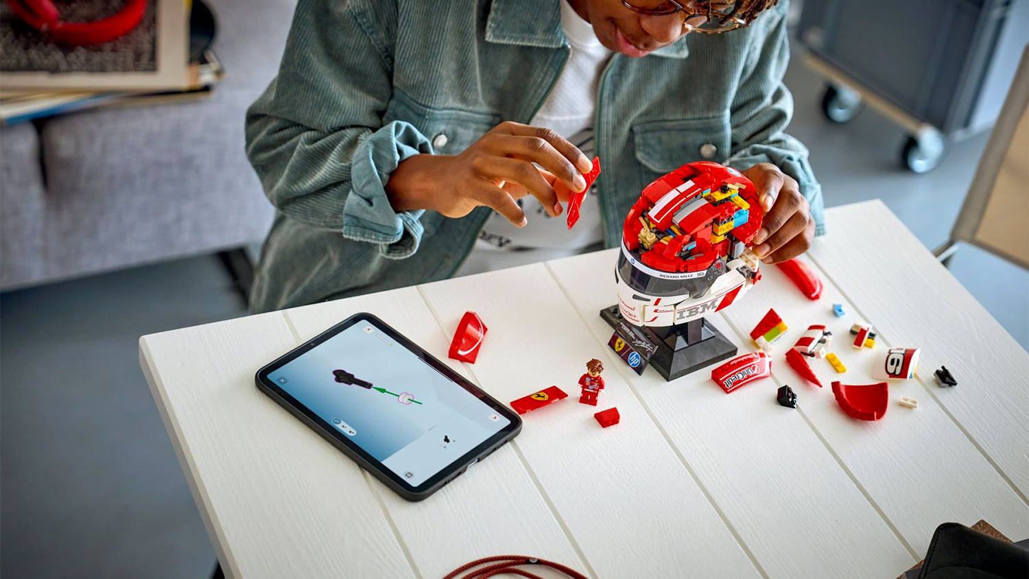 Chlapec stav&iacute; stavebnici LEGO&reg; Editions 43014 Helma Charles Leclerc ze Scuderia Ferrari HP podle aplikace