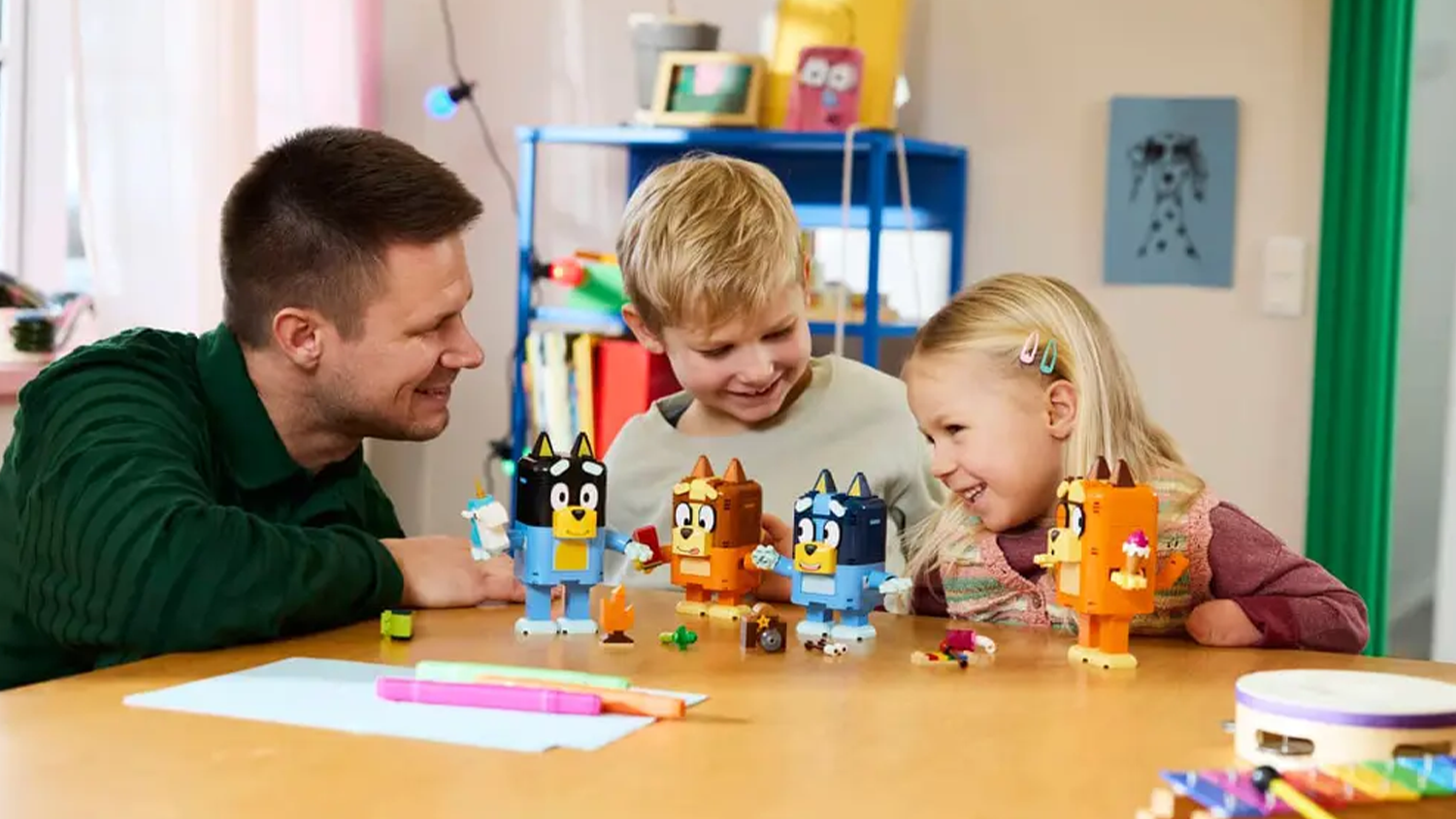 Tatínek s dětmi si hrají s figurkami Bluey