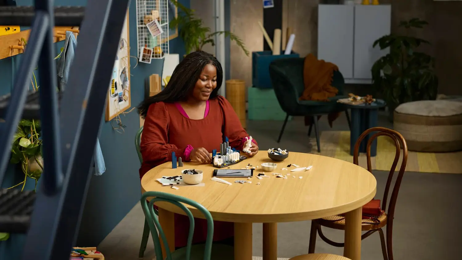 Žena staví stavebnici LEGO® s tabletem na stole