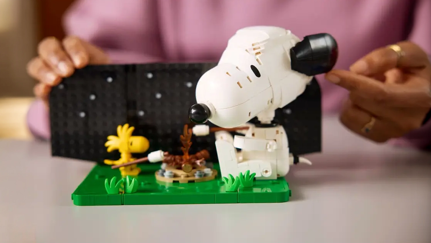 Žena staví stavebnici LEGO® Ideas 21368 Peanuts: Snoopyho bouda