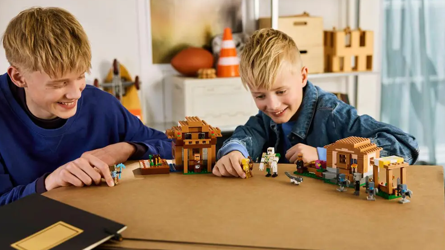 Dva chlapci si hrají se stavebnící LEGO® Minecraft 21596 Útok Mága na vesnici