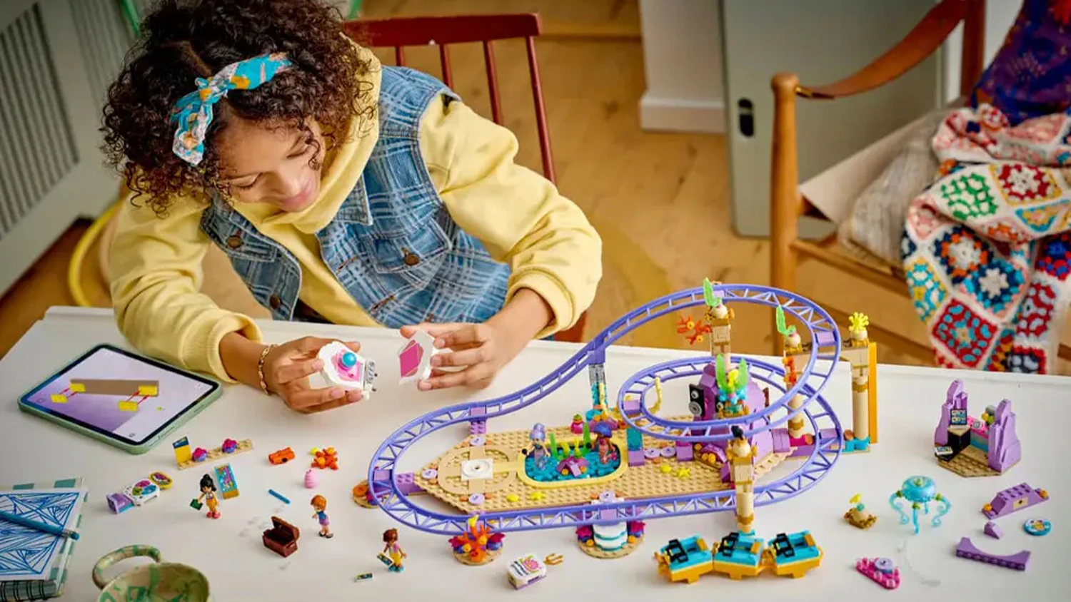 Děvče stav&iacute; stavebnici LEGO&reg; Friends 42703 u stolu
