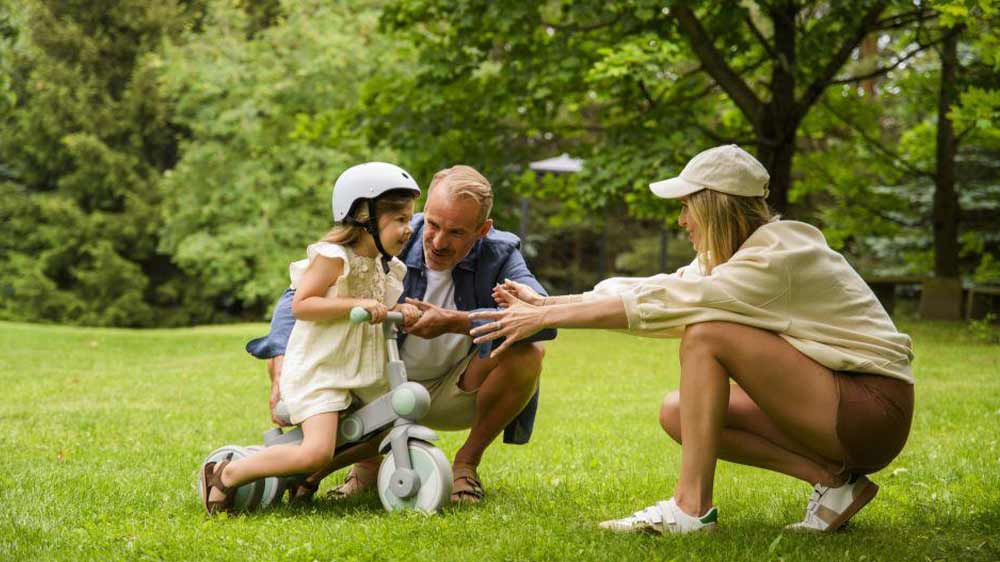 Holčička obklopen&aacute; rodiči použ&iacute;v&aacute; tř&iacute;kolku MoMi SOLIVIA jako odr&aacute;žedlo_02