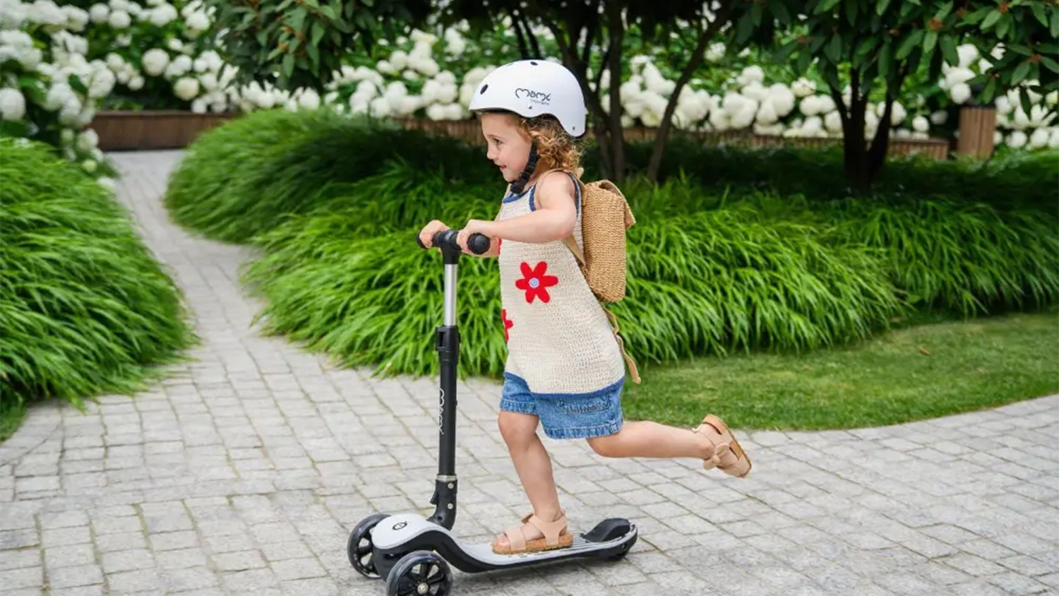 Dievčatko s prilbou jazd&iacute; na ulici na kolobežke MoMi SAN