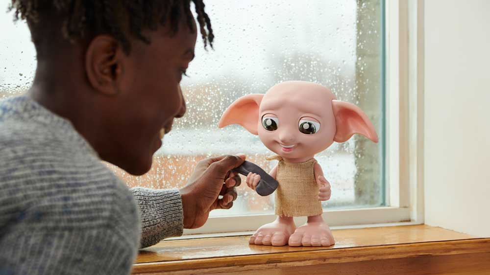 Usměvavý chlapec v šedém svetru dává kouzelnému mluvícímu skřítkovi Dobby ponožku_03