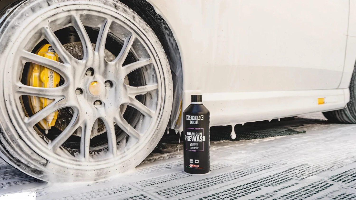 Balen&iacute; aktivn&iacute; pěny MANIAC Foam Gun Prewash 1 000 ml (MF-88) stoj&iacute; před kolem auta nastř&iacute;kan&yacute;m pěnou