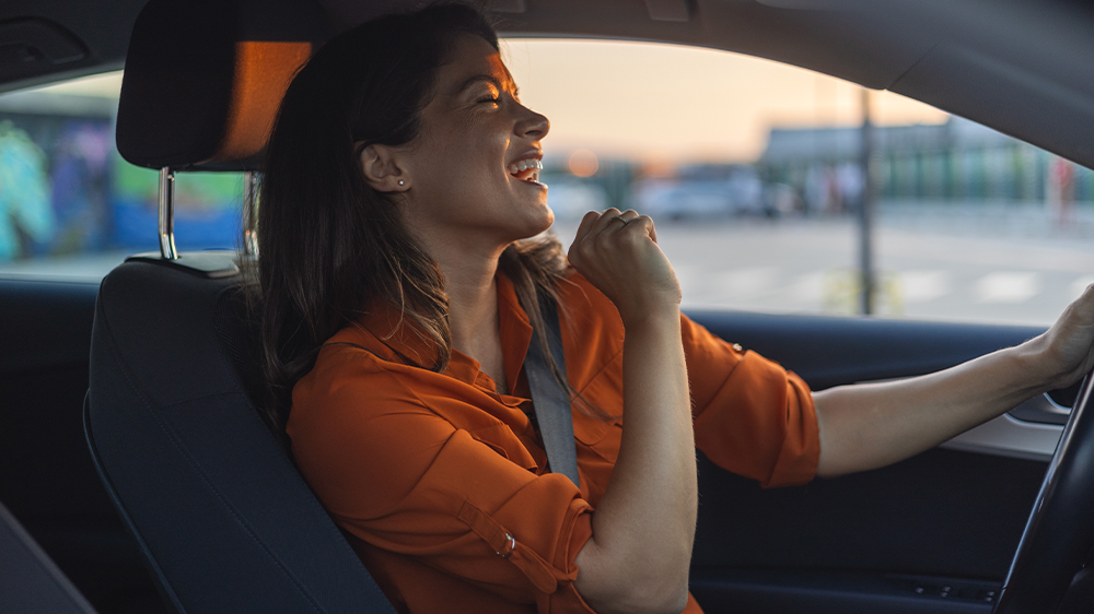 Žena poslouchá hudbu v autě za volantem. Ilustrační snímek_02