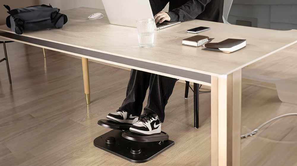 Muž má pod kancelářským stolem podstavec pod nohy Powerton fitness stepper_02