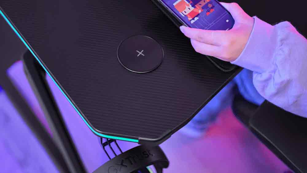 Člověk pokl&aacute;daj&iacute;c&iacute; telefon na nab&iacute;ječku ve stole Trust GXT 710_04