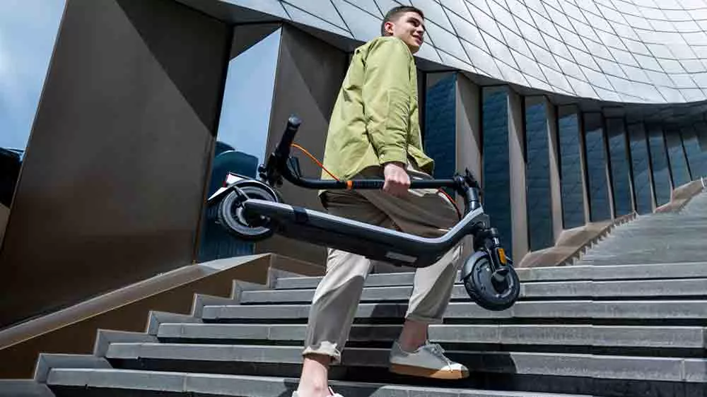 Muž nesie elektrickú kolobežku Segway eKickScooter E2 Plus E II