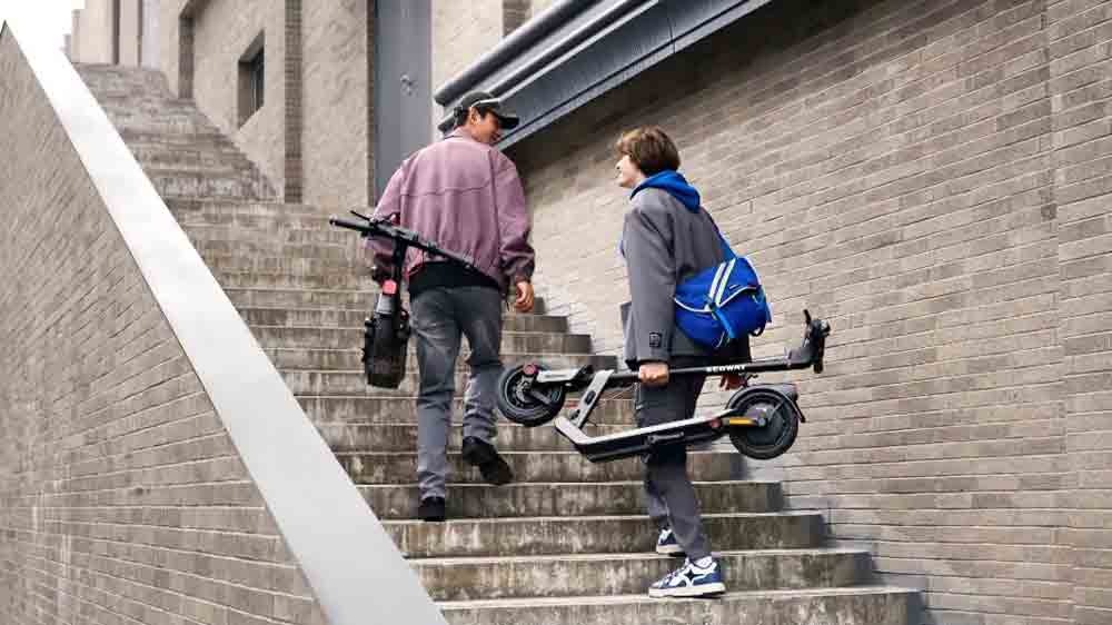 Muži se složen&yacute;mi koloběžkami Segway eKickScooter Ninebot E3 E jdou po schodech_02