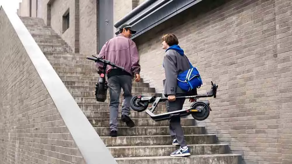Muži so zloženými kolobežkami Segway eKickScooter Ninebot E3 E idú na schodoch_02