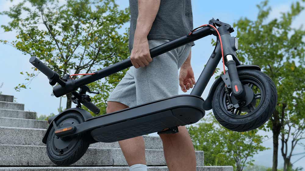 Muž nese složenou elektrickou koloběžku Xiaomi Electric Scooter Elite_04