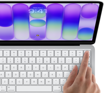 MacBook Neo v striebornej farbe zobrazuje prihlasovaciu obrazovku, niečí prst na senzore Touch ID v pravom hornom rohu klávesnice
