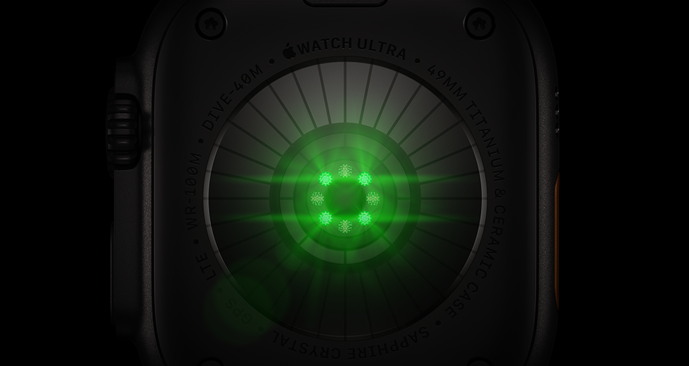 Pohled zezadu na Apple Watch Ultra 4, titanové pouzdro, černá barva, několik kulatých snímačů se svítícími zelenými LED diodami